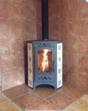 Недорогая печь-камин Бавария угловая с плитой незабудка Амазонка бай фото в интерьере в Бобруйске